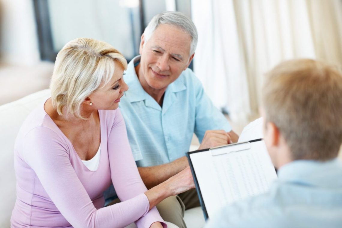 Conseiller en assurance présentant différentes formules à un locataire dans son appartement.