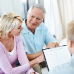Conseiller en assurance présentant différentes formules à un locataire dans son appartement.