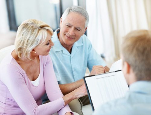 Conseiller en assurance présentant différentes formules à un locataire dans son appartement.
