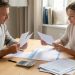 Un homme et une femme examinent des relevés de crédit vierges et un budget mensuel sur une table lumineuse, dans un intérieur français sobre.