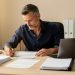 Un investisseur immobilier français examine des documents fiscaux et locatifs vierges sur un bureau lumineux.